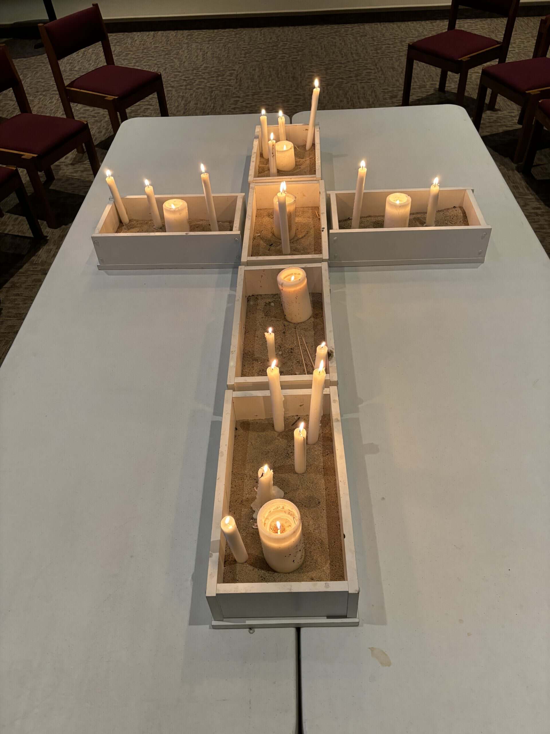 Candles arranged in a cross shape on a table at Gustavus Adolphus Lutheran Church, creating a peaceful and spiritual atmosphere.